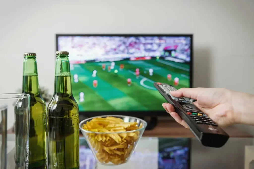 A person with a remote control watching a soccer match